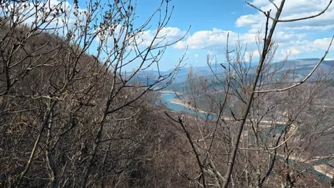 Bare branches frame a distant river valley. Balkan, Eastern Europe, POV Video stock 331814279
