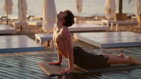 Bare-chested guy took a special strip for yoga and meditation on Sunny Beach in Vídeos de archivo 249843663