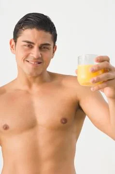 Bare-chested Hispanic man holding orange juice Stock Photos