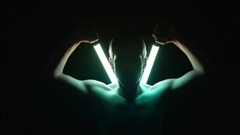 Bare-Chested Man Drawing Two Glowing Neon Tubes from His Back Stock Footage 312318771