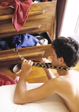 Bare-chested man taking tie from drawer Stock Photos