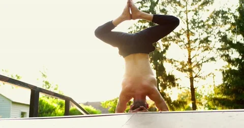 Bare-chested yogi practicing yoga in summer park.Man standing on head face away Stock Footage 156787749