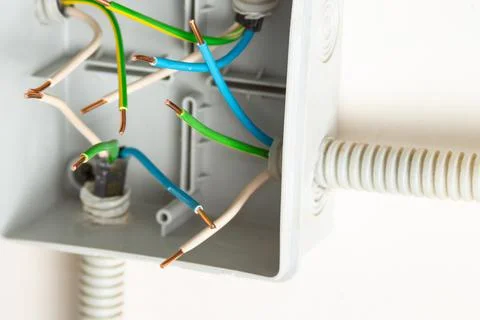 Bare contacts of electrical wires in a junction box on the wall Stock Photos