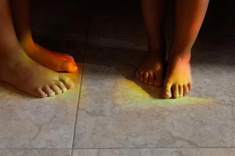 Bare feet of children colored by the diffraction of light. Stock Photos