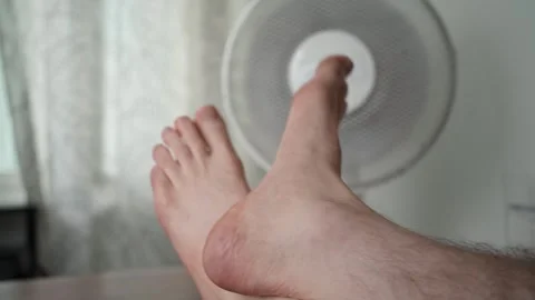 Bare feet cooling in front of electric fan Stock Footage 344692038