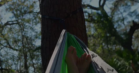 Bare Feet Dangling From Green Hammock Tied Between... Stock Footage 331820789