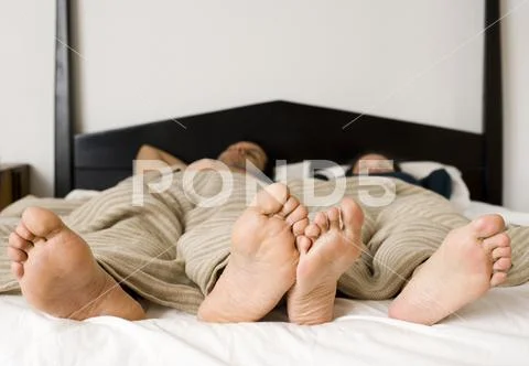 Bare Feet At End Of Bed With Headboard