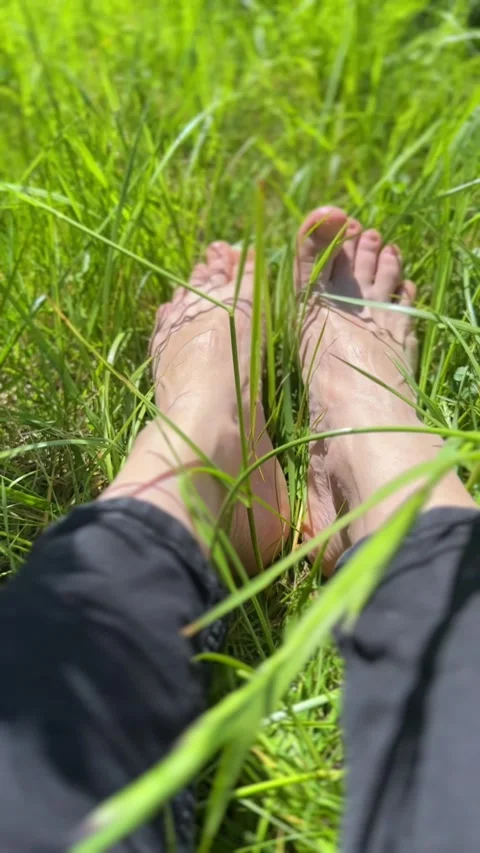 Bare feet resting in lush green grass under the warm sunlight. A symbol of Video stock 312643402