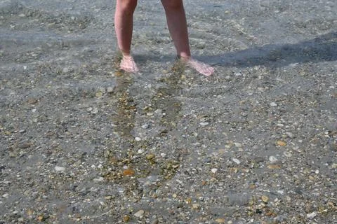 Bare feet standing in shallow clear water Stockfoto's