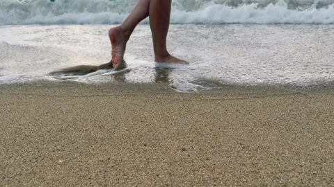 Bare feet touch gentle sea waves on sandy beach. Close-up of relaxing walk Stock Footage 337777176