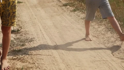 The bare feet of two children run along a dusty sandy village road Stock Footage 231795243