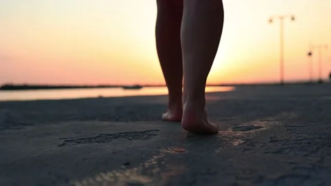 Bare feet walk along the path to the sea, orange sunset Stock Footage 162950271