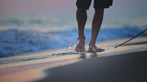 Bare feet walking on wet sand at sunset with gentle waves, cinematic 4K slow Stock Footage 335309516