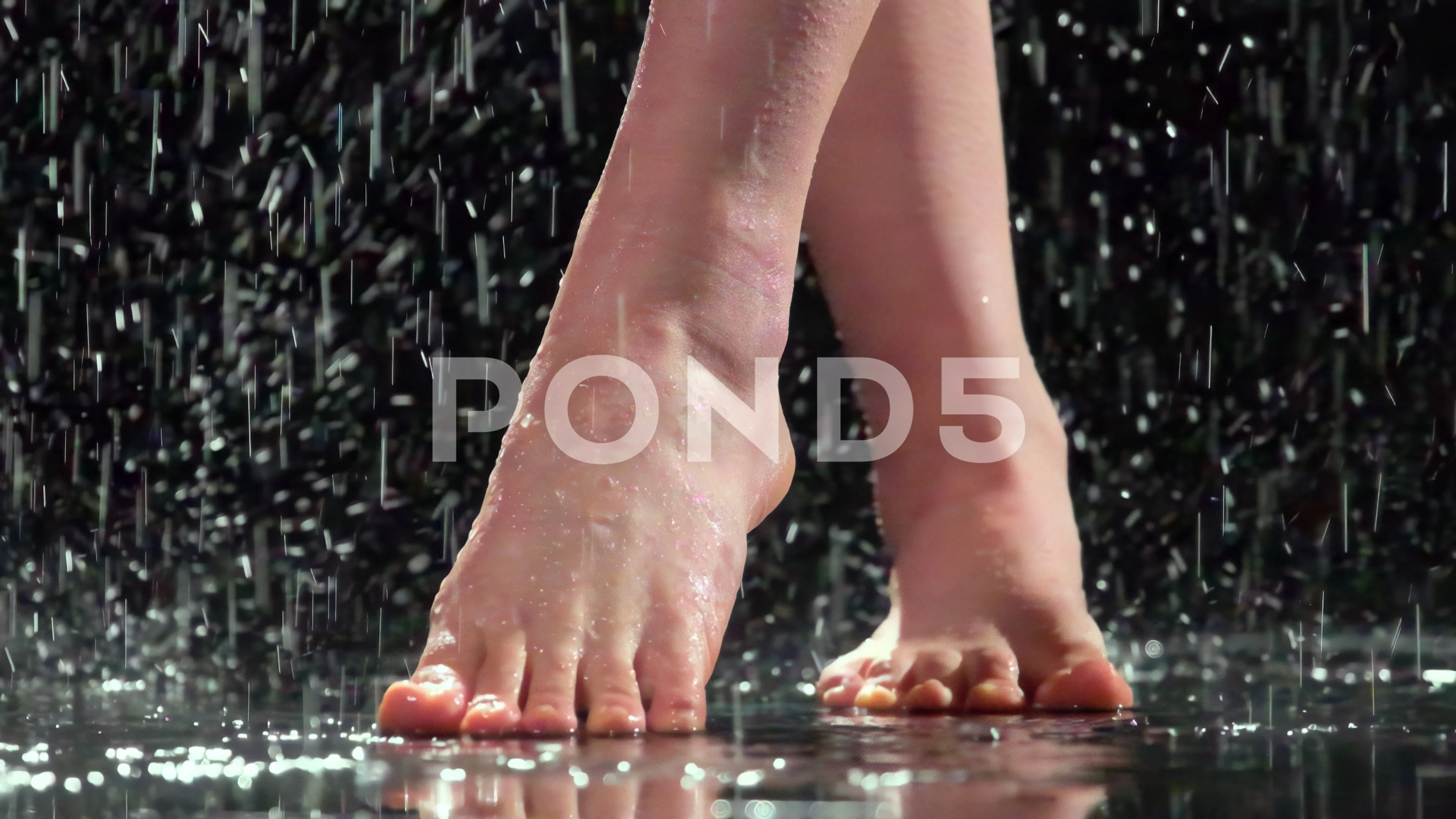 Bare female feet on reflecting surface under rain