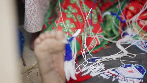 Bare foot anchoring bead thread against floral fabric Stock-Footage 342399282