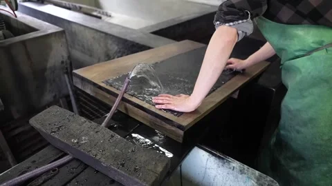 Bare hand presses wet dark cloth flat on a wooden rinsing board while a stream 動画素材 342903839