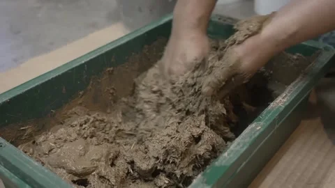 Bare Hands Kneading Thick Wet Mud in a Green Tray Stock Footage 340900984