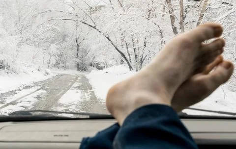 Bare human feet on the windshield panel of the car Stock Photos