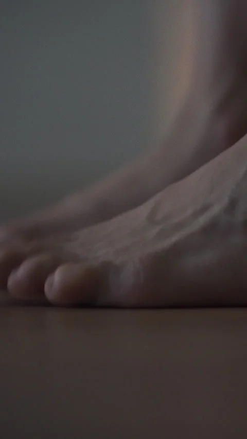 Bare legs swing out bed feet softly landing on wooden floor capturing serene Stock Footage 331535747