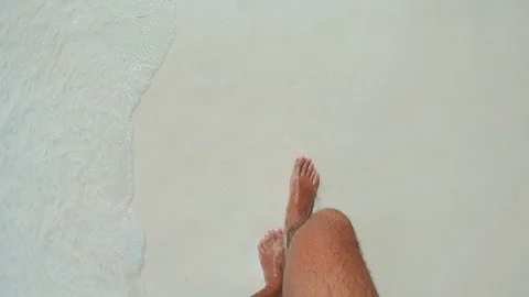 Bare lower leg and foot in shallow beach surf over pale wet sand with bright Stock Footage 338445795