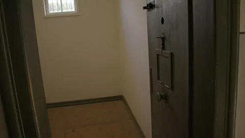 A bare room with a barred window and wooden floor Stock Footage 299042423