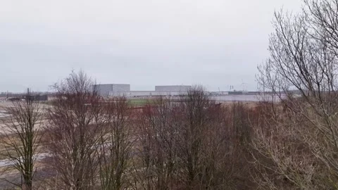 Bare Trees And Peripheral Industrial Structures Along Snowy Coastal Surroundings Stock Footage 325453049