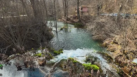 Bare trees line the banks, showing early spring. Grza River Spring, Serbia 스톡 동영상 332372095