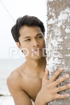 Barechested Man Looking Around Tree Trunk, Close-Up