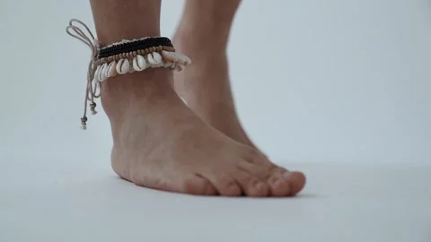 Bared Female Legs With Shells Bracelet on a White Background. Video stock 148940700