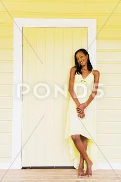 Barefoot african woman leaning against yellow door Stock Photos