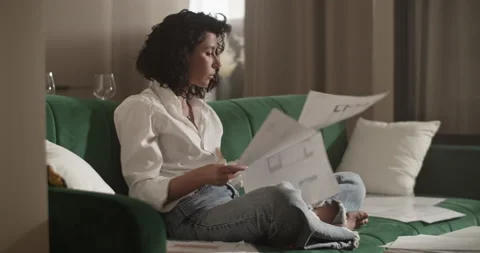 Barefoot architect working with drafts on sofa Stock Footage 207668958