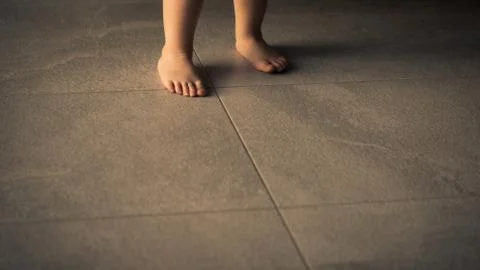 Barefoot baby are staying on heating tile floor. Stock Photos