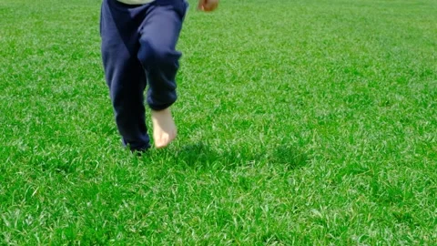 Barefoot boy running across the grass fo... | Stock Video | Pond5