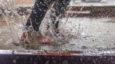 Barefoot of human jumping over a puddle in the rain. Abstract and fashion bac Stock Photos