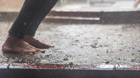 Barefoot of human jumping over a puddle in the rain. . Selective focus. Space Stock Photos