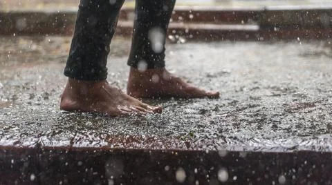 Barefoot of human jumping over a puddle in the rain. . Selective focus. Space Stock Photos
