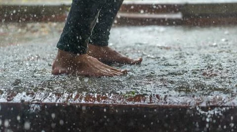 Barefoot of human jumping over a puddle in the rain. Abstract and fashion bac Stock Photos