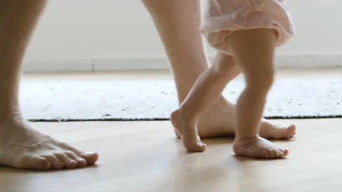 Barefoot infant learning walking with help of father Stock Footage 143947742