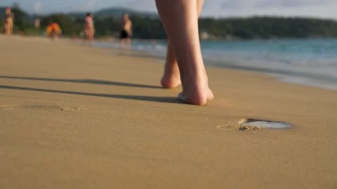 Barefoot lady walks along empty ocean beach under blue sky Stock Footage 133225729