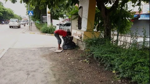 Barefoot man digs through trash bag on street, traffic, road, Vientiane, Laos Vídeos de archivo 75823338