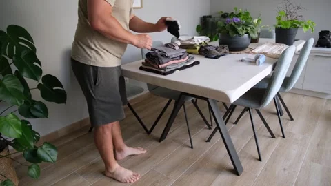 Barefoot man doing laundry folding clothes at home Stock Footage 345733610