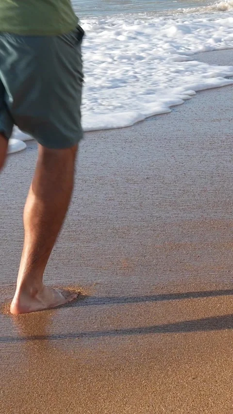 Barefoot man running on sandy beach, creating temporary footprints on the sand Video stock 308877898
