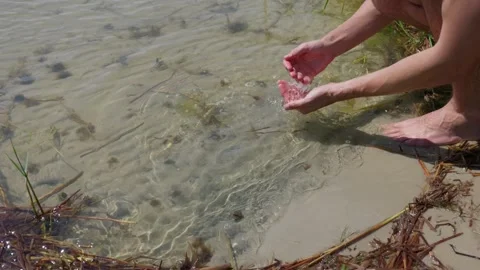 Barefoot Man Scooping Clear Water with Hands in Shallow Lake 스톡 동영상 342765673