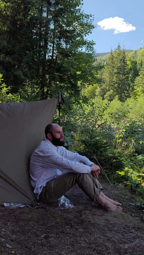 Barefoot Man Sitting by Camping Tarp Shelter in Summer Forest Video stock 345065611