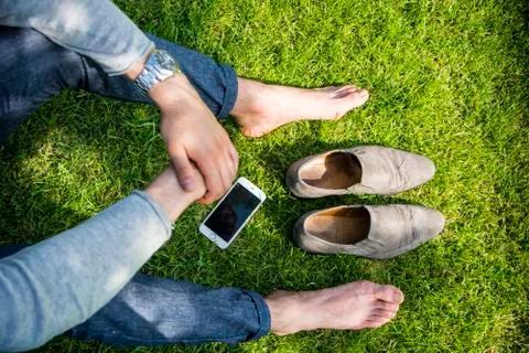 Barefoot man sitting on grass Stock Photos