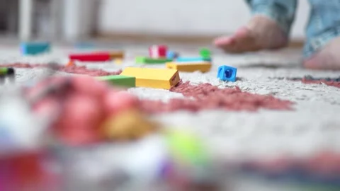 Barefoot Man Stepping on Toy Block on Hardwood Floor - 4K. Video stock 331637894