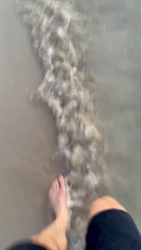 Barefoot man walking through shallow seawater along a tropical beach in Vídeos de archivo 345888774