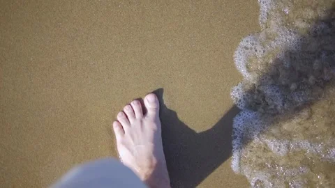 Barefoot steps along the beach as waves lap around, capturing a tranquil an.. Stock Footage 292766030