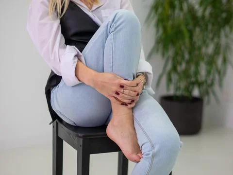 Barefoot Woman Sitting on Stool Hugging Her Knee Stock Photos