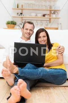 Barefoot young couple relaxing with a laptop Stock Photos